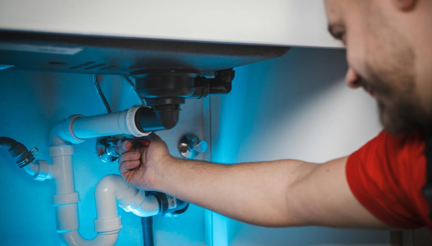 man-working-on-kitchen-sink-plumbing